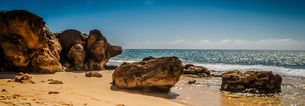 A coast with large rocks on the beach